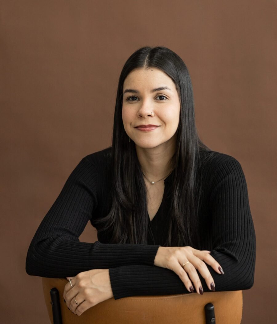 Retrato profissional de Mariana Nascimento, psicóloga, sentada com os braços apoiados em uma cadeira.